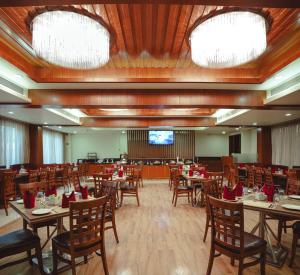 a dining room with tables and chairs and a screen at Ramee The Srinivas Palace in Bhuj
