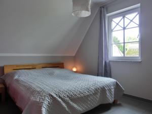 ein weißes Schlafzimmer mit einem Bett und einem Fenster in der Unterkunft Ferienhaus FH T 1d in Graal-Müritz