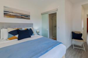a bedroom with a bed with blue pillows and a chair at Onofre Setúbal House in Setúbal