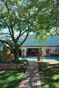 a house with a tree and a brick walkway at Sunninghill Guest Lodges in Johannesburg