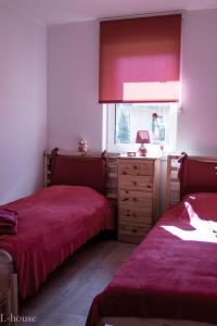 two beds in a bedroom with red sheets and a window at Vacation house in Saulkrasti
