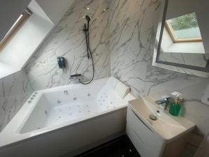 a bathroom with a white tub and a sink at Le Duplex Balnéo Maison climatisée in Saint-Martin-du-Tertre
