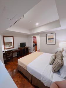 a bedroom with a large white bed and a desk at Olympia Makati Studio former Somerset Olympia Makati in Manila