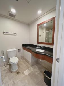 a bathroom with a toilet and a sink and a mirror at Olympia Makati Studio former Somerset Olympia Makati in Manila