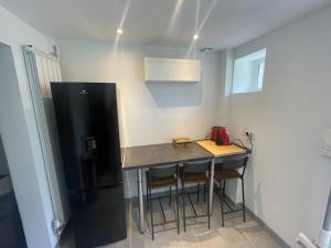 une petite cuisine avec une table et un réfrigérateur dans l'établissement Le Duplex Balnéo Maison climatisée, à Saint-Martin-du-Tertre 6 autres photos