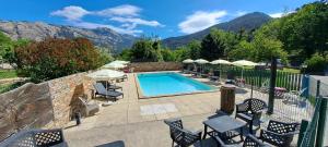 a swimming pool with chairs and umbrellas in front of mountains at Scopa Rossa in Evisa