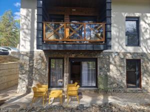 dom z żółtymi krzesłami i balkonem w obiekcie Divčigora apartmani w mieście Divčibare