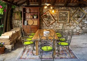 een houten tafel met stoelen en een stenen muur bij Heritage Villa Baković in Dubrovnik