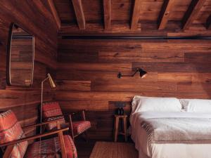 卡尼略的住宿－L´Ovella Negra Mountain Lodge，卧室设有木墙和一张床及椅子