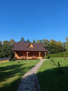 a log cabin with a slate roof on a lawn at Domek u Heli in Limanowa
