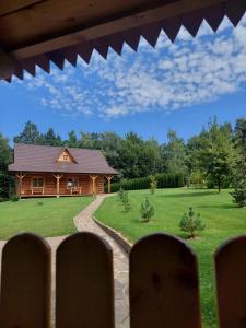 a log cabin with a yard and a house at Domek u Heli in Limanowa
