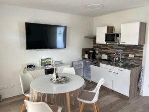 a kitchen with a table with chairs and a tv on the wall at Tamaris Resort in Graal-Müritz