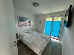 a small bedroom with a bed and two windows at Tamaris Resort in Graal-Müritz