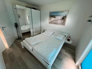 a small bedroom with a bed and a mirror at Tamaris Resort in Graal-Müritz