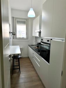 une cuisine avec des placards blancs, une table et un tabouret dans l'établissement Bicocca Modern Apartment, à Milan