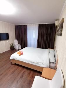 een slaapkamer met een groot wit bed en houten vloeren bij Квартира in Nikolayev