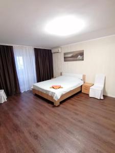 1 dormitorio con cama blanca y suelo de madera en Квартира, en Mykolaiv