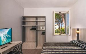 a bedroom with a bed and a desk and a window at Hotel Apuana in Marina di Pietrasanta