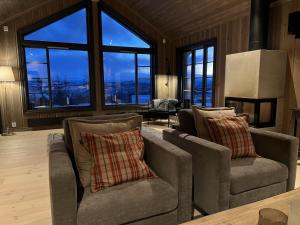 a living room with two chairs and a fireplace at Ny flott høyfjellshytte på Geilo! 8 min til Kikut in Geilo