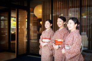 three women dressed in kimonos standing outside a building at Dogo Onsen Yachiyo 道後温泉八千代 in Matsuyama