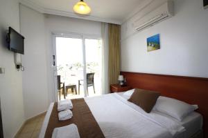 Cette chambre comprend un lit et une grande fenêtre. dans l'établissement Bonapart Hotel, à Çeşme