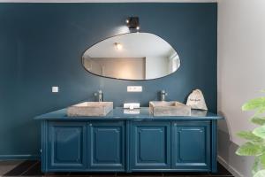 a blue bathroom with two sinks and a mirror at Fall Eighteen by Romy&Travis in Bruges