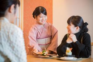 two women sitting at a table eating food at Dogo Onsen Yachiyo 道後温泉八千代 in Matsuyama