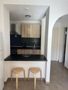 a kitchen with two stools and a black counter at Maspalomas tisalaya park in Maspalomas