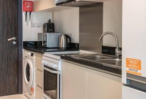 a kitchen with a sink and a washing machine at AWS Homes - Modern Living in Top Location in Dubai