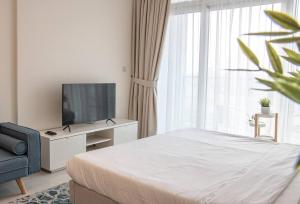 a white bedroom with a bed and a television at AWS Homes - Modern Living in Top Location in Dubai