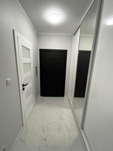 a hallway with two mirrors and two doors at Apartament Studzienna in Elblag