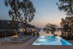 a pool with lounge chairs next to a body of water at oKEAnõs in Vourkari