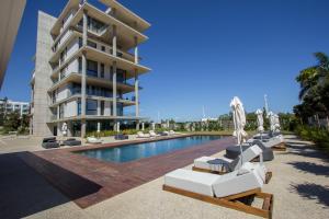 a swimming pool with lounge chairs and a building at Shanti Tranquil Escapes in Paralimni