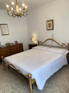 a bedroom with a bed with white sheets and a chandelier at Bed & Breakfast Casa Marinella in Lenna