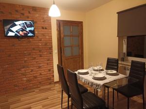 a dining room table with chairs and a tv on a brick wall at Apartamenty i domki in Wołkowyja