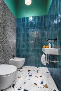 uma casa de banho em azulejos azuis com um WC e um lavatório em Apartamenty Pomarańczarnia em Poznań