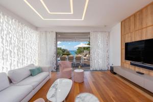 a living room with a white couch and a television at Villa Calla ZadarVillas in Petrcane