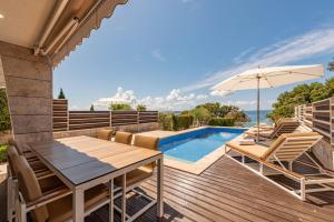 um pátio com uma mesa e cadeiras e uma piscina em Villa Calla em Petrcane