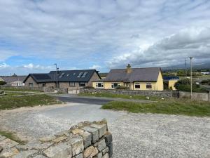 a house with a stone wall next to a road at Seafront cottage Dinas Dinlle in Caernarfon