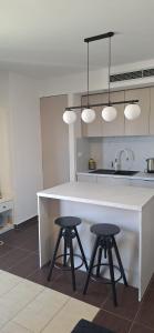 a kitchen with a white counter and two stools at Vitas Apartments in Zaton