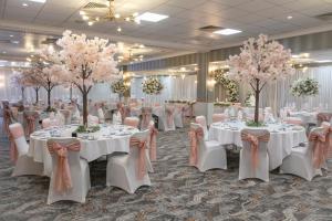 a banquet hall with white tables and pink trees at The Suites Hotel & Spa Knowsley - Liverpool by Compass Hospitality in Knowsley
