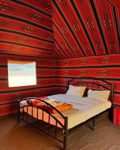 ワディ・ラムにあるDesert Bird Campの赤い壁のドミトリールームのベッド1台分です。