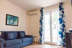 sala de estar con sofá azul y puerta corredera de cristal en Blu Sun Apartment in Complesso Riva del Sole, en Giovinazzo