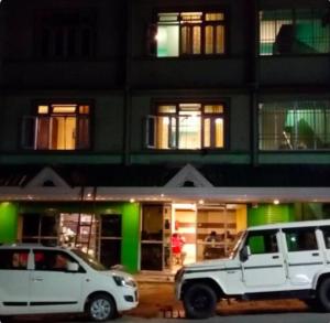 dos vehículos blancos estacionados frente a un edificio en GreenDot 2BHK Pure veg, en Gangtok
