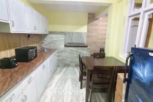 cocina con armarios blancos, mesa y fregadero en GreenDot 2BHK Pure veg, en Gangtok