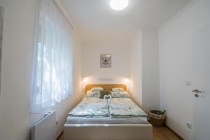 Una habitación blanca con una cama y una ventana en Menta Apartman, en Siófok