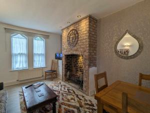a living room with a brick fireplace and a table at Victoria Villas in Sandycroft