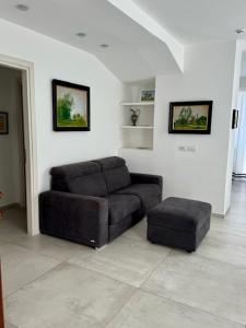 un sofá y un taburete en la sala de estar en Hotel CineApollo - Ogni camera un film! en Messina