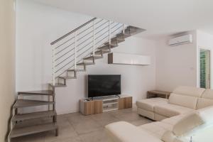 a living room with a staircase and a television at Le Dune Verdi in Lido di Jesolo