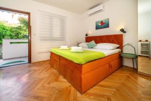 een slaapkamer met een oranje bed met een groene matras bij Apartment & Double Room Dean in Baška